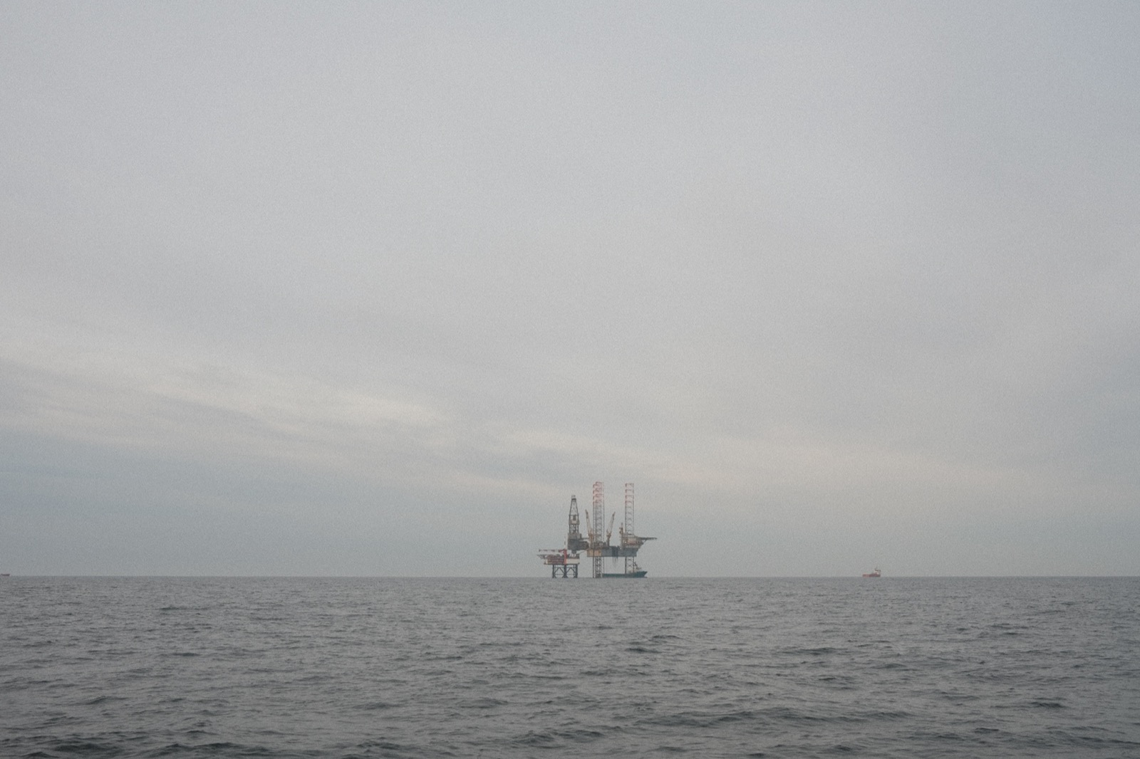 An oil rig off the coast, visible in the grey haze