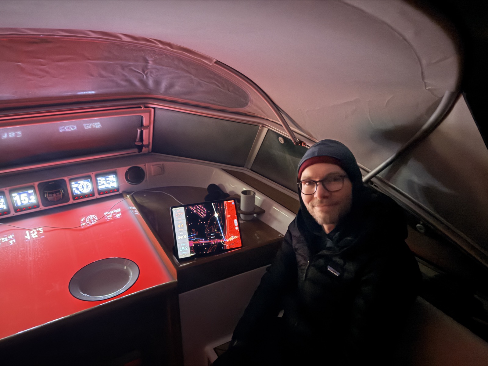 On watch at the nav station — chart plotter, tea, and red cockpit lighting