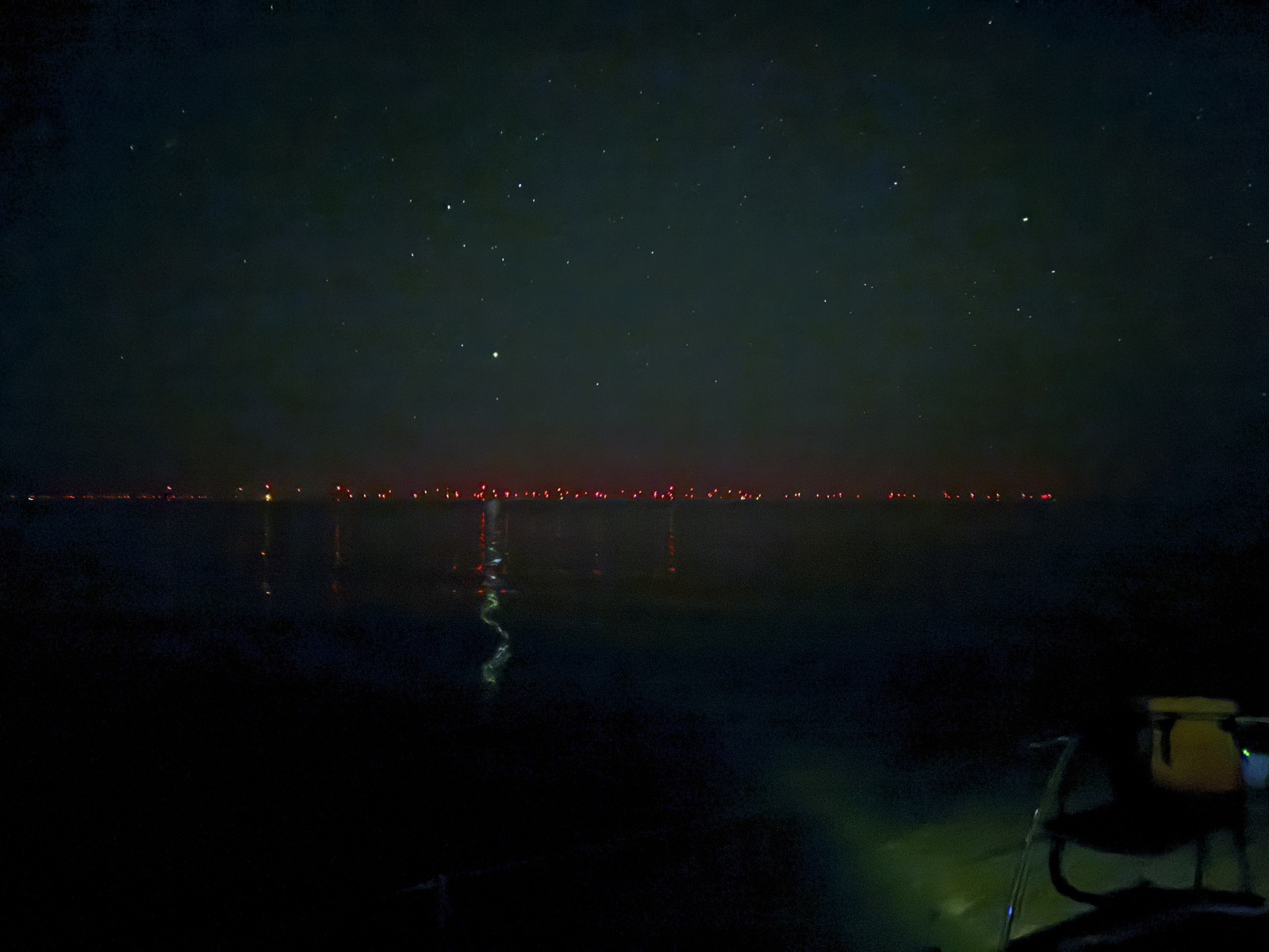 Wind farm lights on the horizon at night, stars overhead