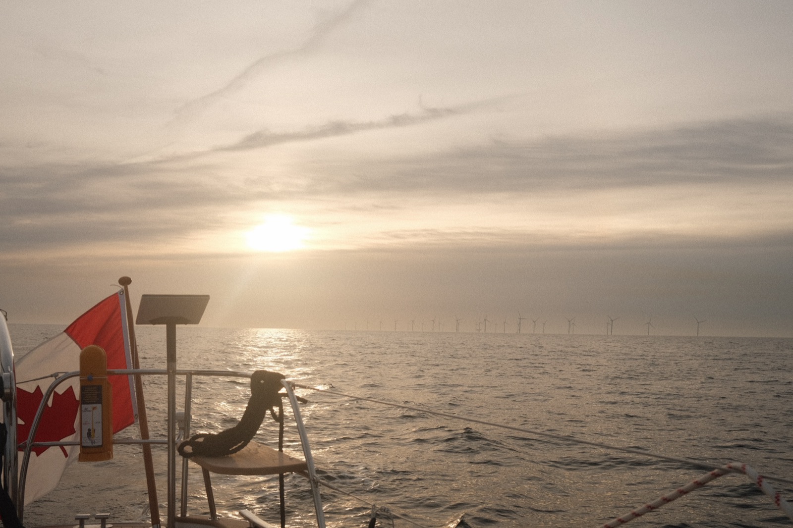 The Canadian flag flies off the stern as we pass a wind farm at sunrise