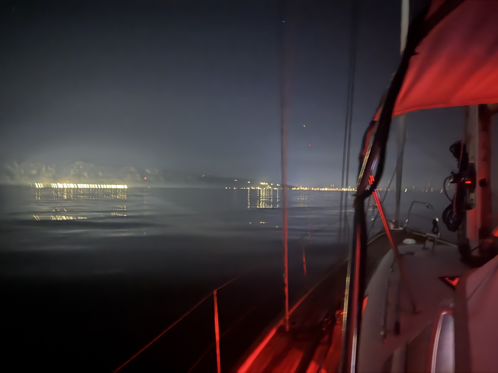 Approaching Shëngjin's lights in the dark, lit red by the boat's night lighting