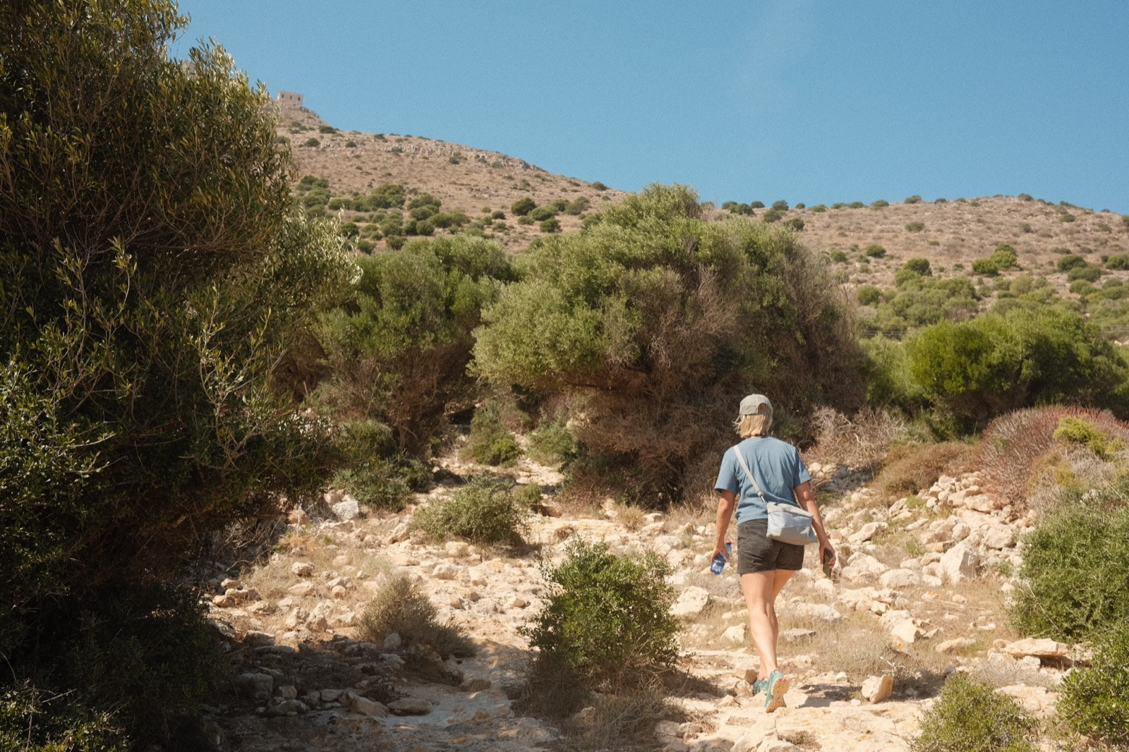 Hiking up a rocky trail through the scrub toward the castle on Favignana