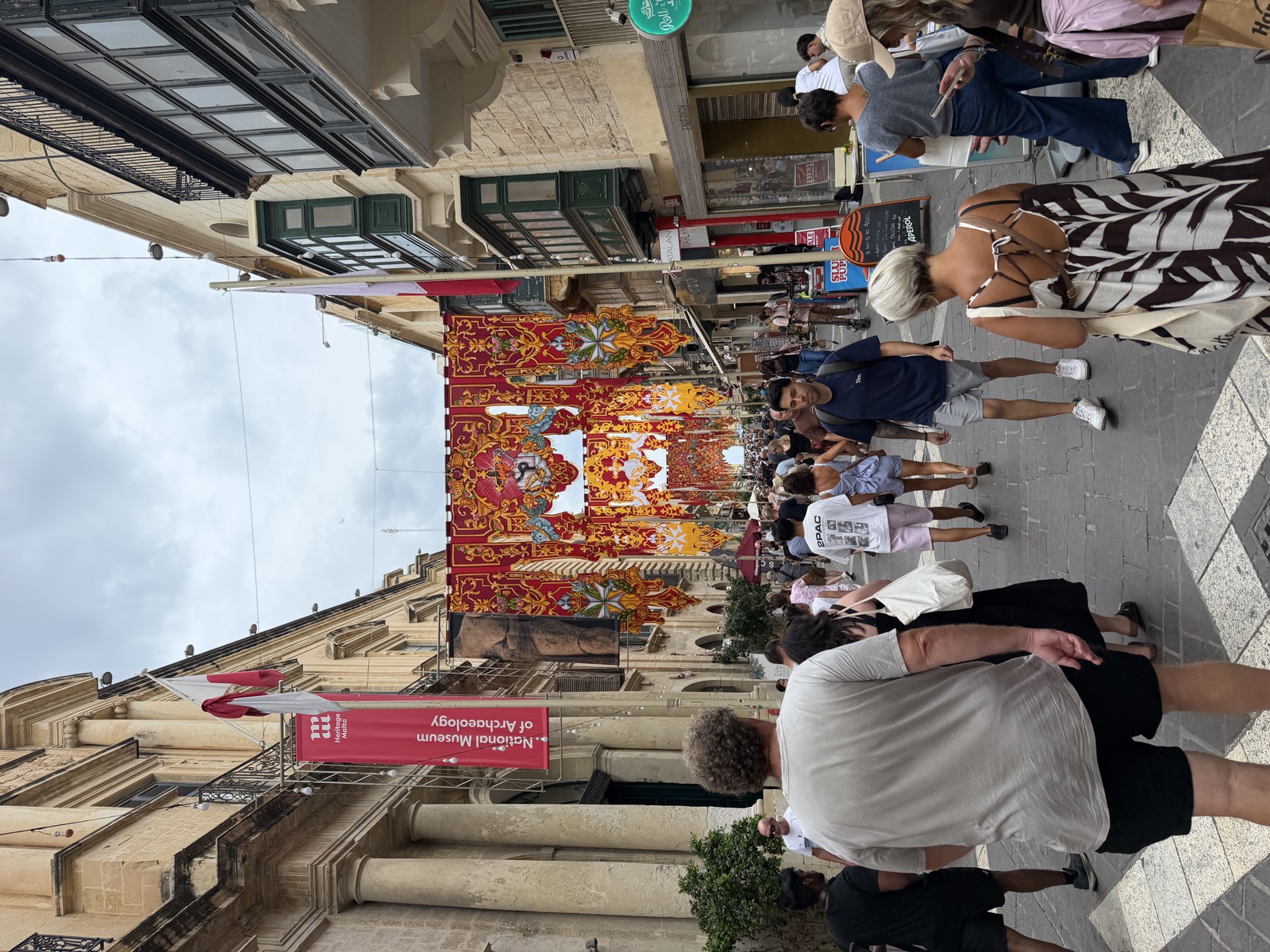 Crowds on Republic Street in Valletta under red and gold festa banners